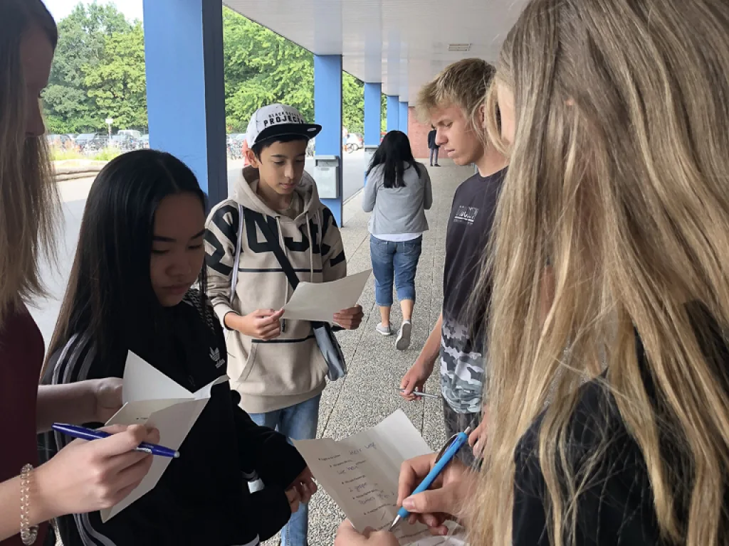 Jugendliche notieren etwas auf Zetteln im Schulgebäude.